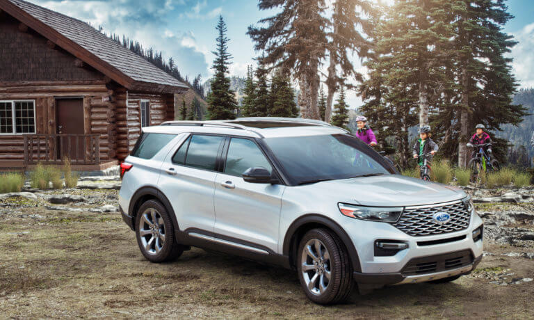 2024 Ford Explorer parked by a cabin with a family